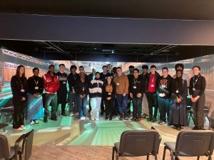 Students standing inside an immersive 360‑degree parliamentary simulation with digital projections covering the walls and floor.