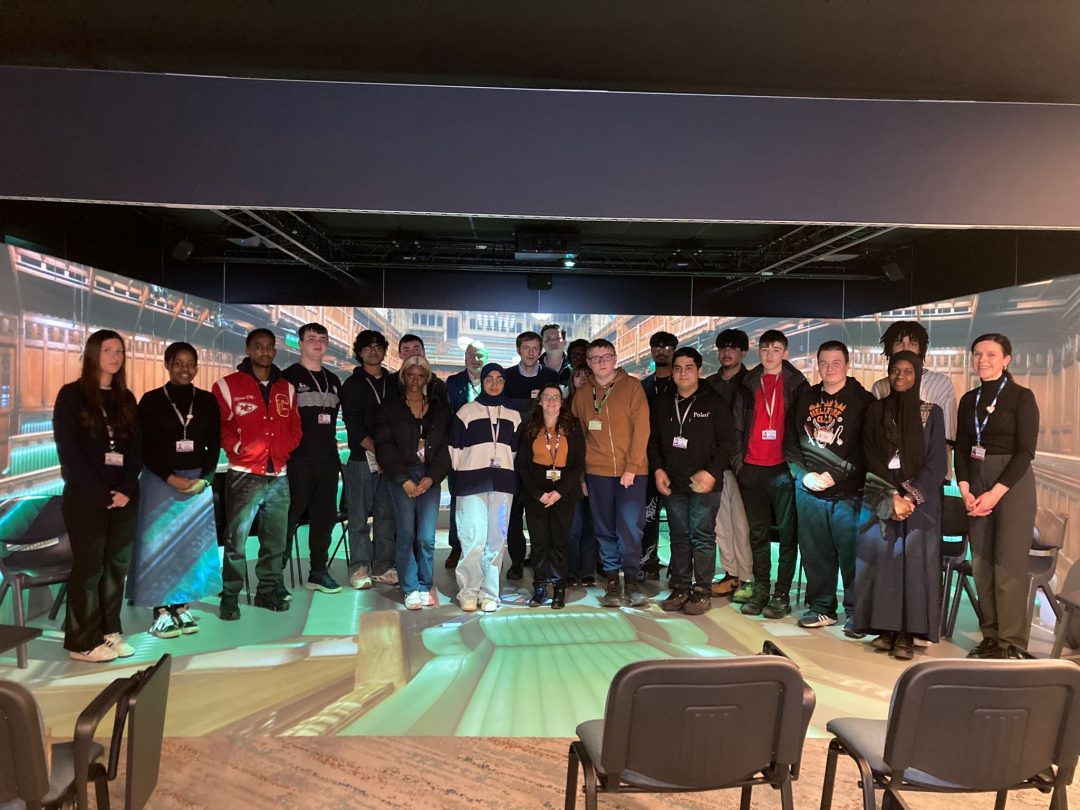 Students standing inside an immersive 360‑degree parliamentary simulation with digital projections covering the walls and floor.